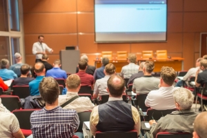 Business speaker giving a talk in conference hall.